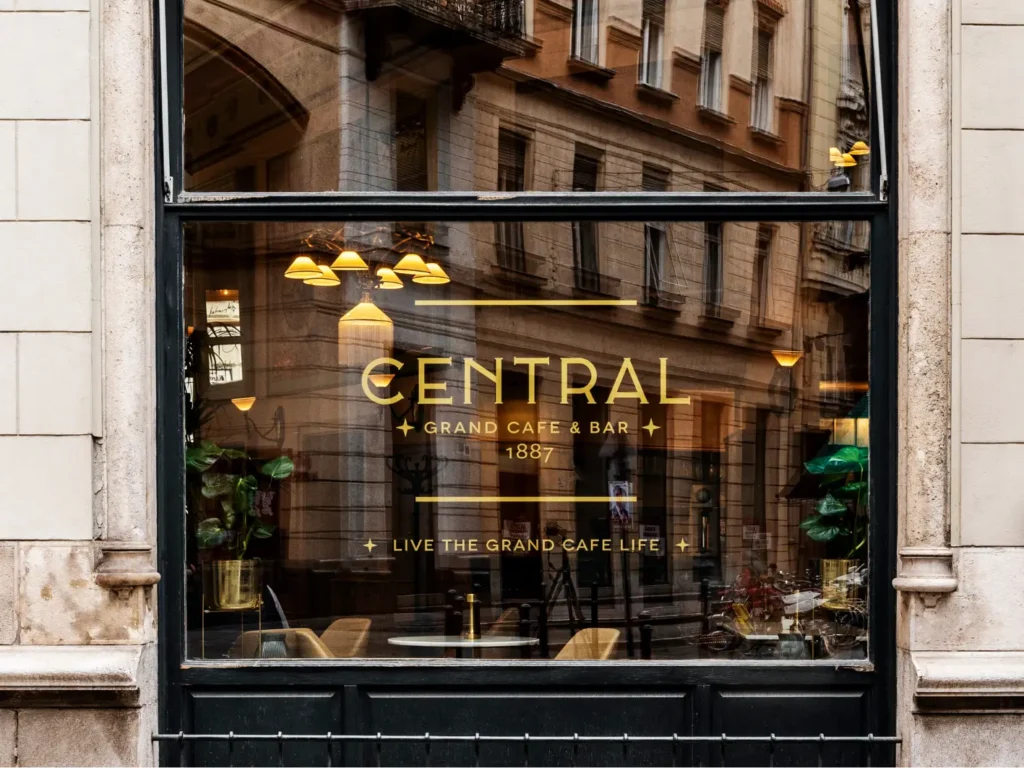 historic café in Budapest Centrál’s shop window with gold lettering: Central Grand Cafe & Bar 1887 – Live the Grand Cafe Life