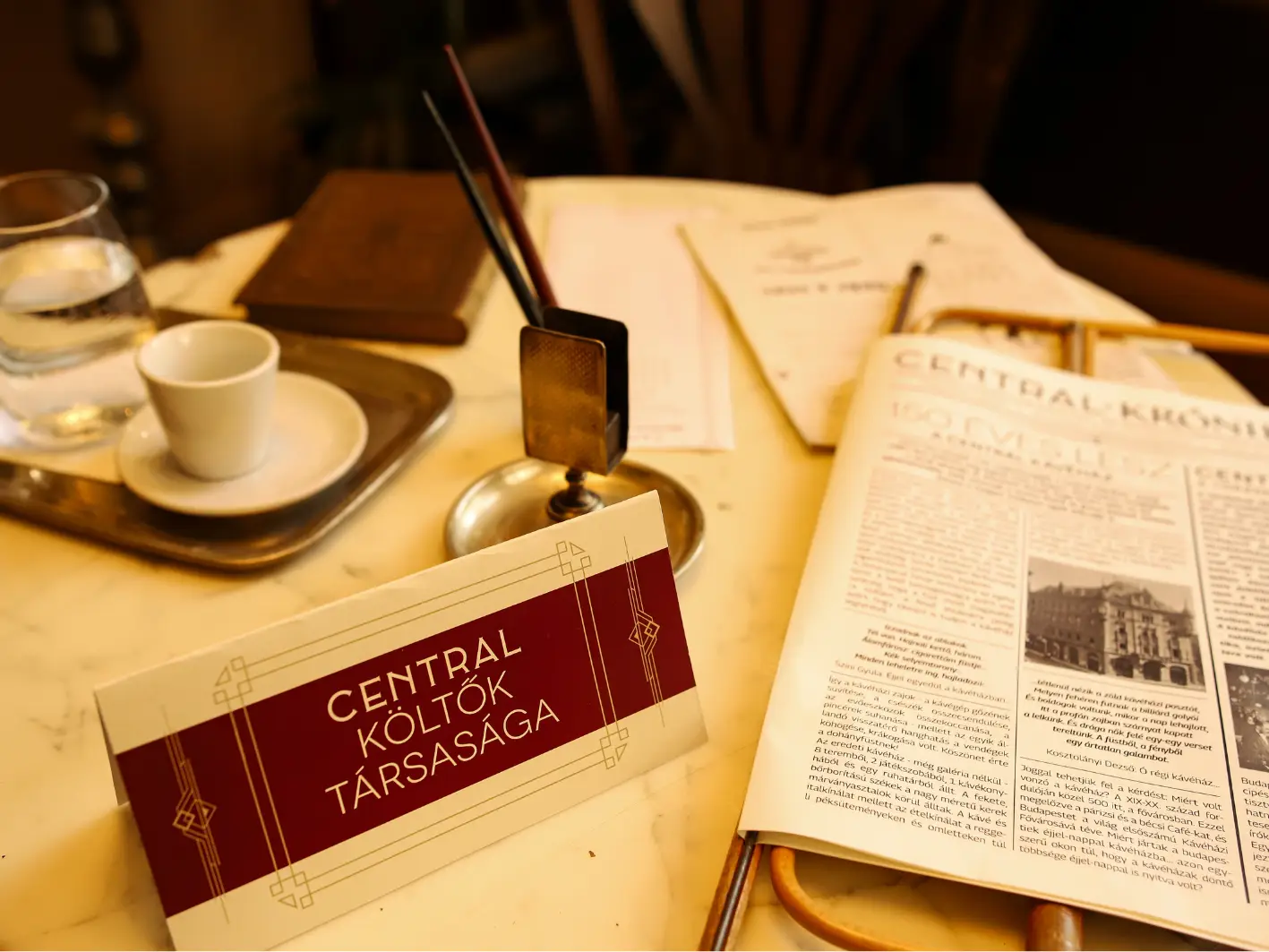 Central Költők Társasága (Society of Poets) table card on a marble table with an espresso cup and Centrál Krónika